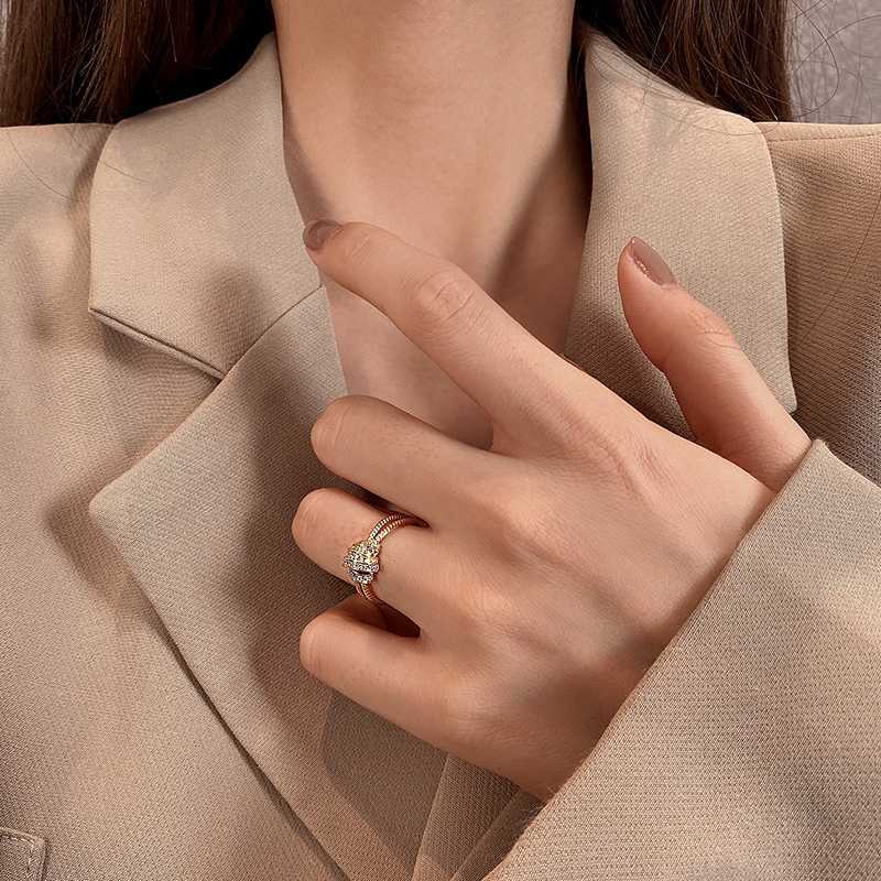Close-up of a hand wearing a ring with a green gemstone against a beige background