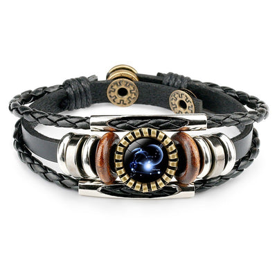 A black leather bracelet with braided and smooth bands. Features a metallic centerpiece with a celestial design, flanked by wooden and metallic accents. Elegant and modern.