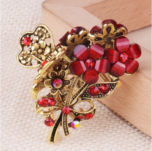 Decorative hair clip with red gemstones and gold detailing on a textured surface