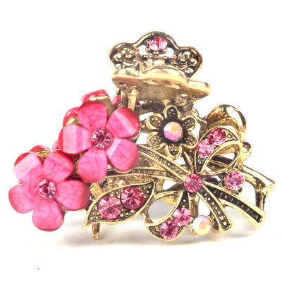 Gold hair clip with pink floral and leaf designs on a white background