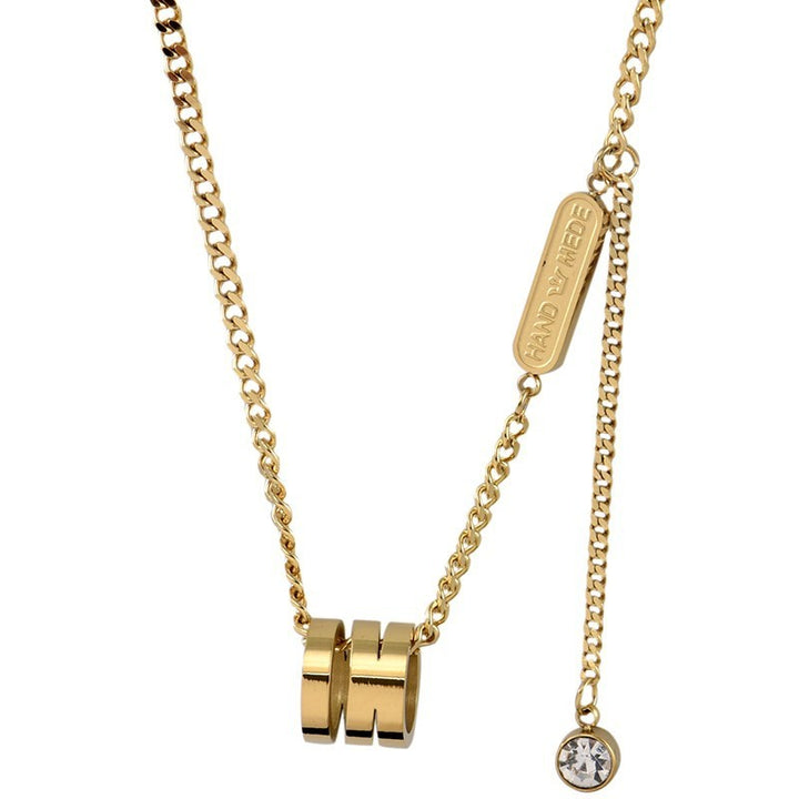 Gold tone  necklace with cylindrical pendants and a round pendant on a white background