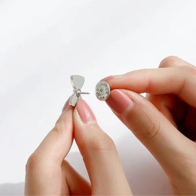 Close-up of hands holding enamel pin against a light background
