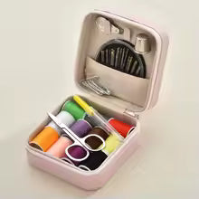 pink Sewing kit with colorful threads, scissors, and other tools in a teal case on a beige background