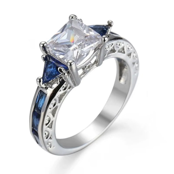 Silver ring with a large central zircon and smaller blue stones on a white background