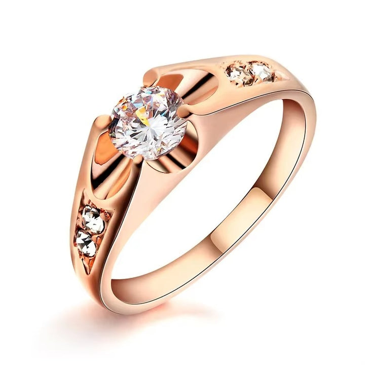 Rose gold ring with a large zircon and smaller zircon s on a white background