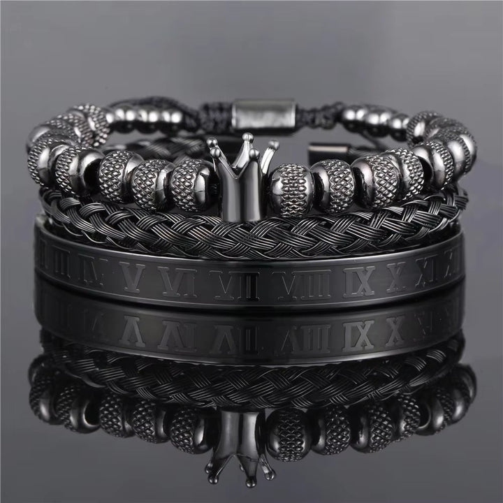 Stack of black and silver bracelets on a reflective surface with a gray background