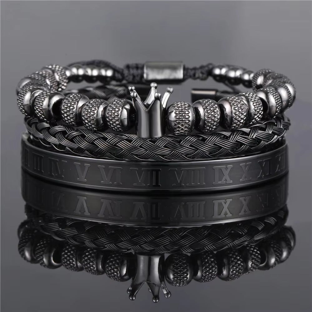 Stack of black and silver bracelets on a reflective surface with a gray background