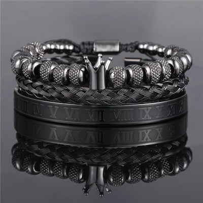 Stack of black and silver bracelets on a reflective surface with a gray background