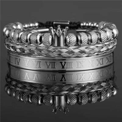 Stack of silver bracelets with braided design and Roman numeral detailing on a reflective surface.