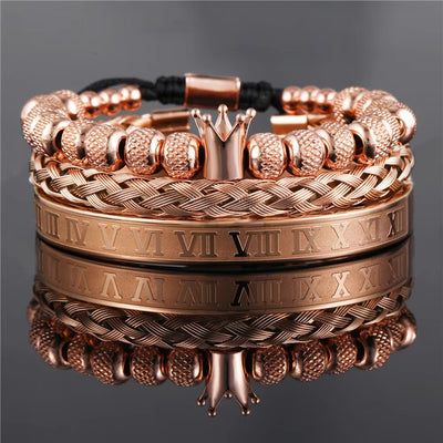 Rose gold bracelets with crown and Roman numeral design on a reflective surface