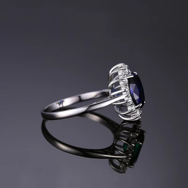 Silver ring with a blue gemstone on a reflective surface