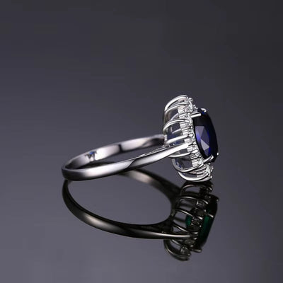 Silver ring with a blue gemstone on a reflective surface