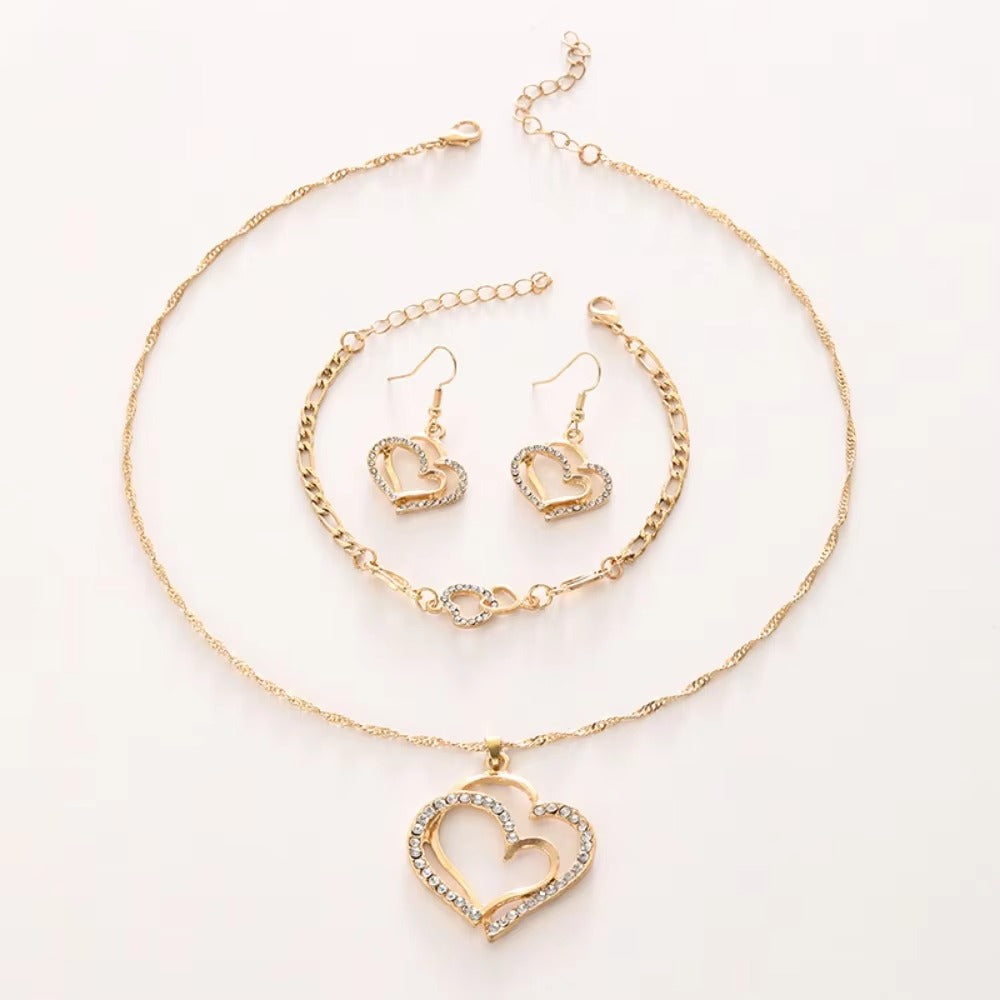 Gold heart-shaped jewelry set including necklace, bracelet, and earrings on a white background