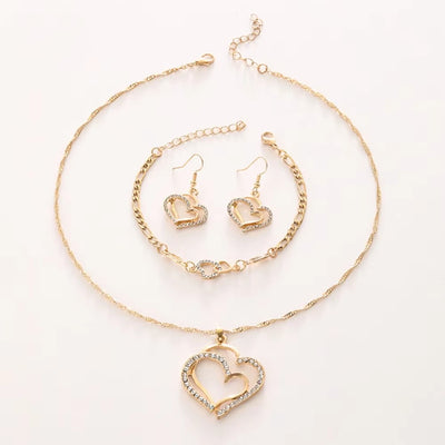 Gold heart-shaped jewelry set including necklace, bracelet, and earrings on a white background
