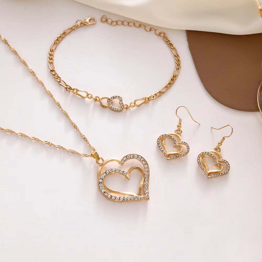 Gold heart-shaped necklace and earrings on a white surface