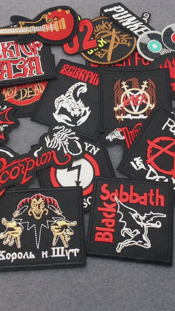 video of a Collection of various patches with different designs and text on a gray surface.