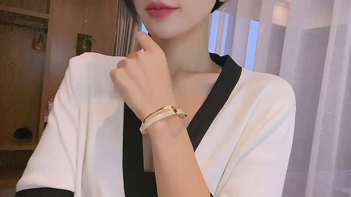 video of a woman wearing Gold and pearl bracelet in a room background