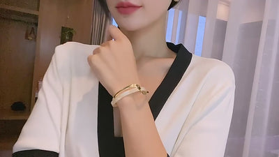 video of a woman wearing Gold and pearl bracelet in a room background