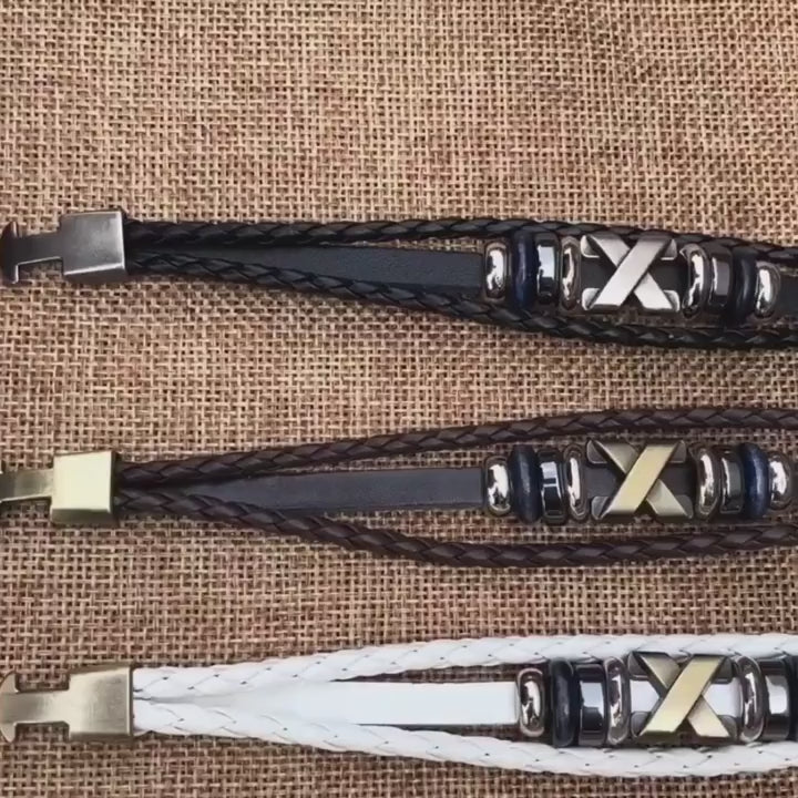video of Three braided leather bracelets with metal clasps on a textured surface
