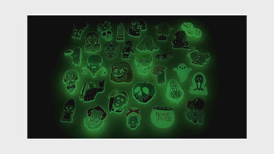 video of an Assorted green glow-in-the-dark shoe charms on a black background