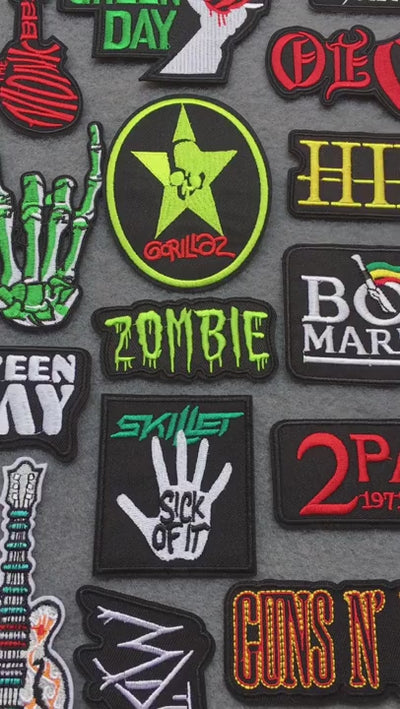 video of Iron-on embroidered band logo patches including Queen, Green Day, KISS, Slayer, Muse, and more on grey background