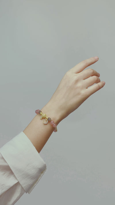 video showing Bracelet with pink beads and gold charms on a  hand 