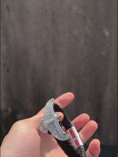 video of Black braided bracelet with an eagle clasp held in a hand against a dark background